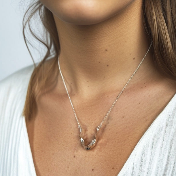 Woman wearing a silver mandible necklace, showcasing how the anatomical jawbone pendant sits elegantly on the chest.