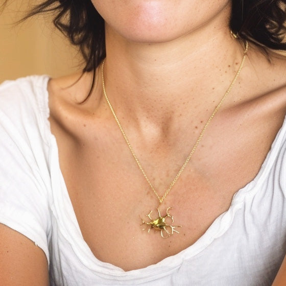 Model wearing the Melanocyte necklace in gold vermeil — elegant science jewelry featuring the branching structure of a melanocyte cell.
