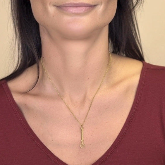 Close-up of a woman wearing the gold vermeil microRNA necklace, highlighting the delicate design against her skin and burgundy top.
