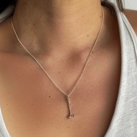 Close-up of a woman wearing the sterling silver myosin necklace with a V-neck top, showing the necklace’s fine detail and delicate length