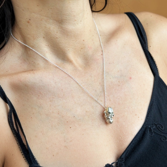 Woman wearing an orangutan skull pendant necklace in sterling silver, symbolizing intelligence and conservation – science-inspired jewelry.