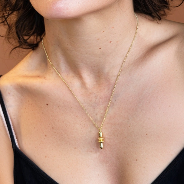 Woman wearing the gold vermeil orbital necklace, showing how the science-inspired pendant rests elegantly at mid-chest level.