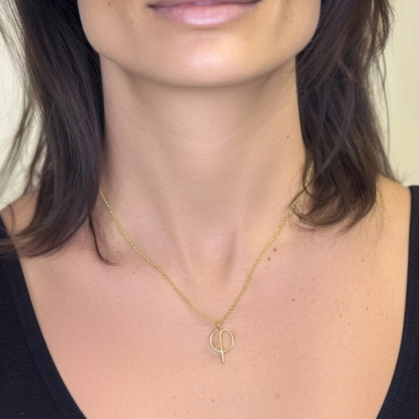 Close-up of a woman wearing the Phi Necklace in gold vermeil, highlighting the pendant’s elegant geometry on her neckline.