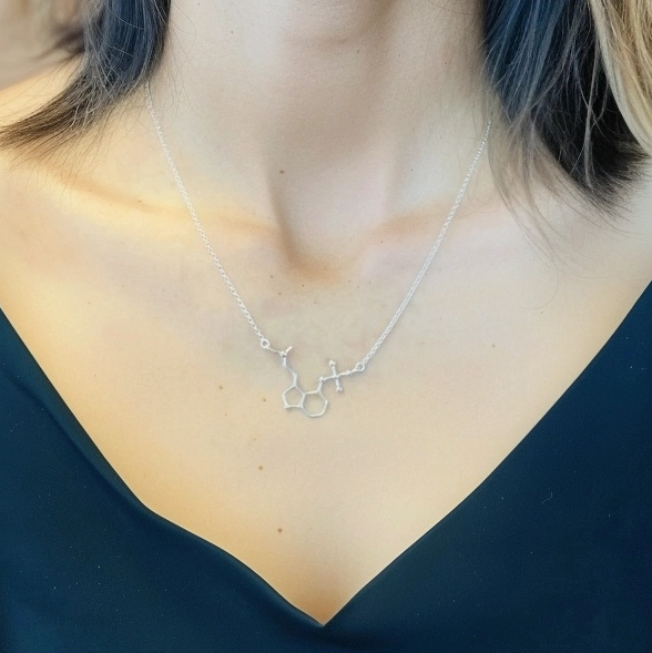 Close-up of a psilocybin necklace resting on the wearer’s collarbone, highlighting the intricate details of the molecule.