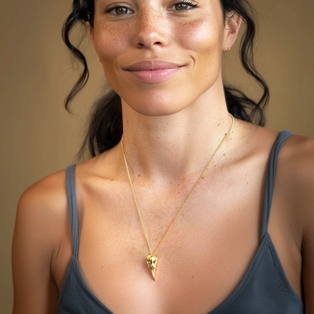 Woman wearing Gold Vermeil Raven Skull Necklace – unique science and nature inspired jewelry, perfect for biologists, writers, and lovers of the macabre.