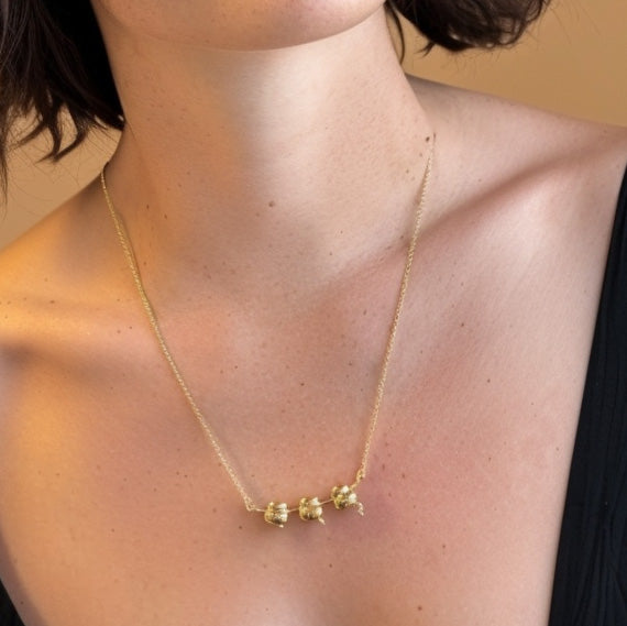 Close-up of a woman wearing the gold vermeil ribosome necklace against a neutral backdrop, highlighting the pendant’s ribosomal structure on the collarbone.