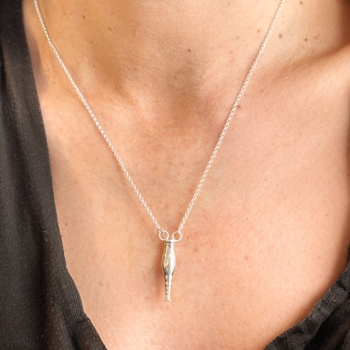 Rotifer necklace pendant in sterling silver worn on a chain, shown on a person’s neck.