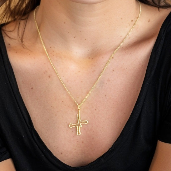 Woman wearing the gold vermeil tRNA necklace layered with another chain, showing the cloverleaf-shaped pendant resting elegantly against the neckline.
