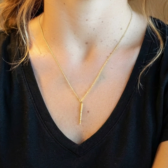 Close-up of the gold vermeil telescope necklace resting on a woman’s neck, highlighting the pendant’s length and shine.