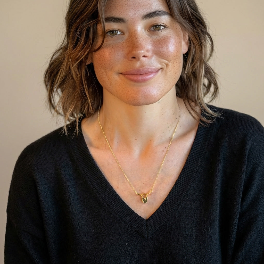 Woman wearing a gold vermeil thoracic vertebra necklace, shown in a close-up portrait to highlight size and how the pendant sits on the chest.