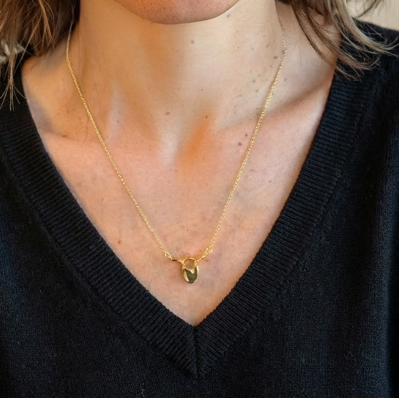 Close-up view of the gold vermeil thoracic vertebra necklace layered on a woman’s neckline, showing the anatomical pendant in everyday wear.