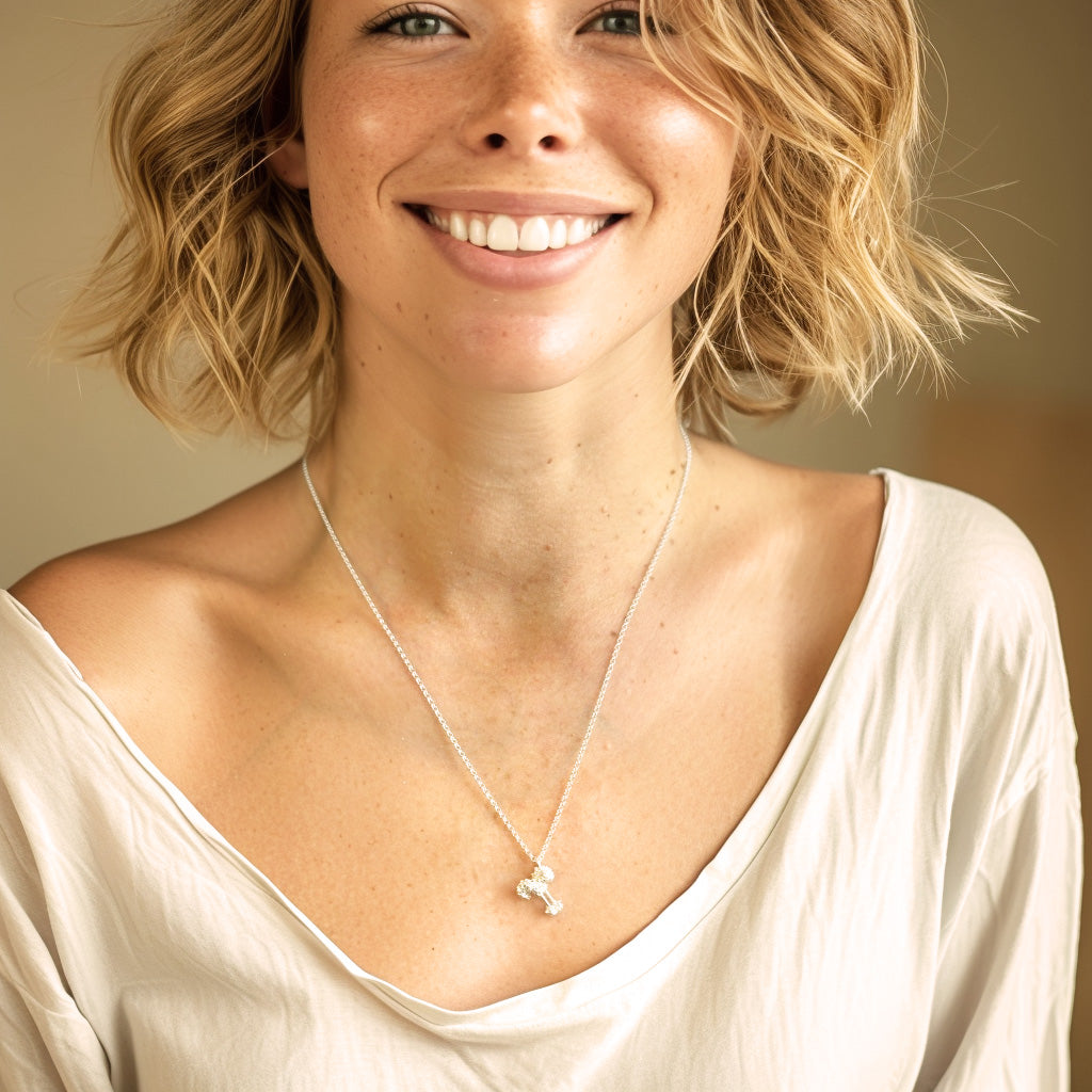 Smiling woman wearing a cream-colored top and the toll-like receptor necklace, showcasing the jewelry's size and how it sits elegantly on the chest.