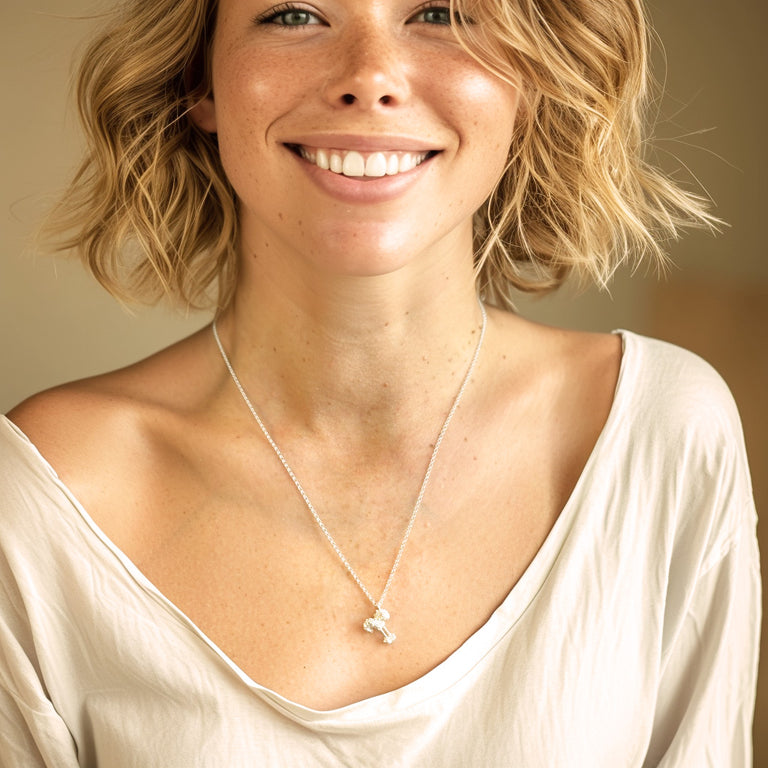 Smiling woman wearing a cream-colored top and the toll-like receptor necklace, showcasing the jewelry's size and how it sits elegantly on the chest.
