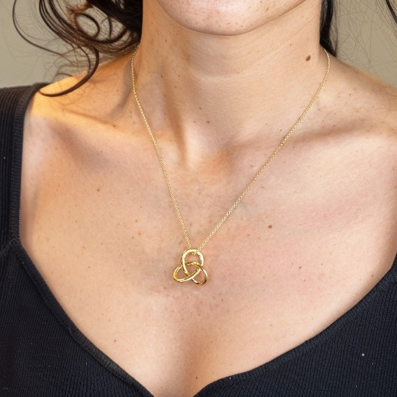 Close-up of the Trefoil Knot Necklace in gold vermeil worn on the neck, highlighting the pendant’s three-loop mathematical knot design and subtle geometric symmetry.