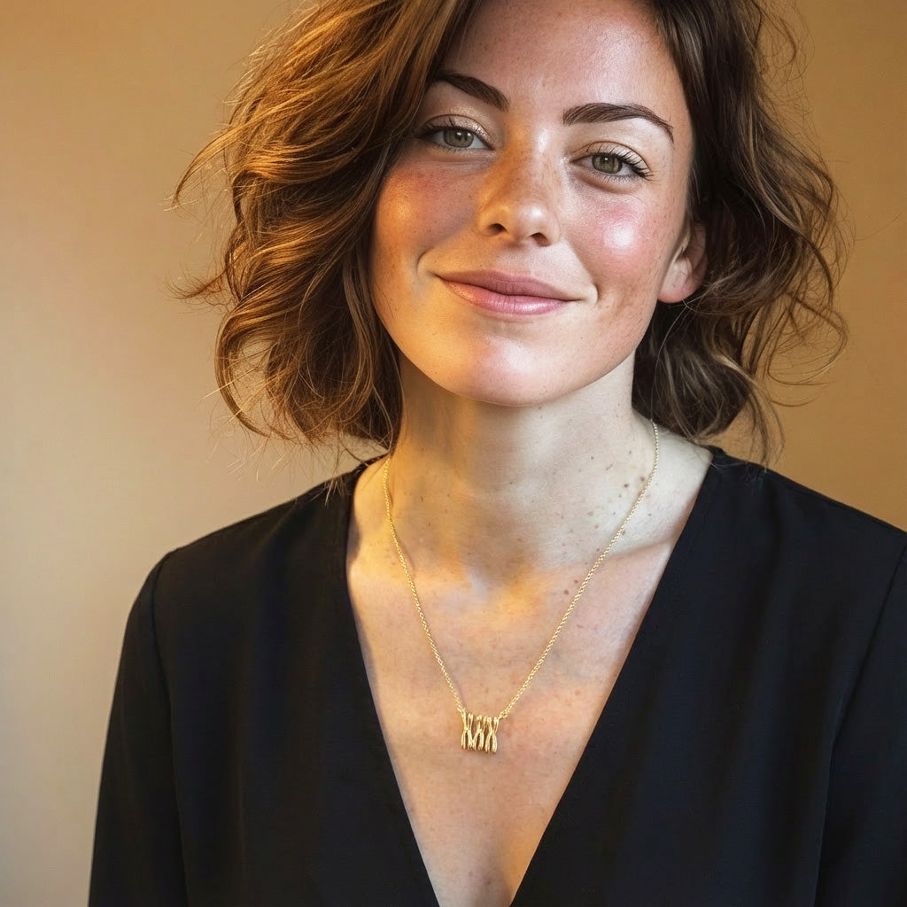 Woman wearing a gold vermeil Trisomy 21 necklace, shown in a close-up portrait, highlighting the delicate three-strand chromosome design.