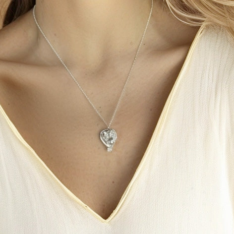A close-up of a woman’s neck wearing the twin fetus necklace in sterling silver. The delicate chain complements the pendant, which rests just above the collarbone.