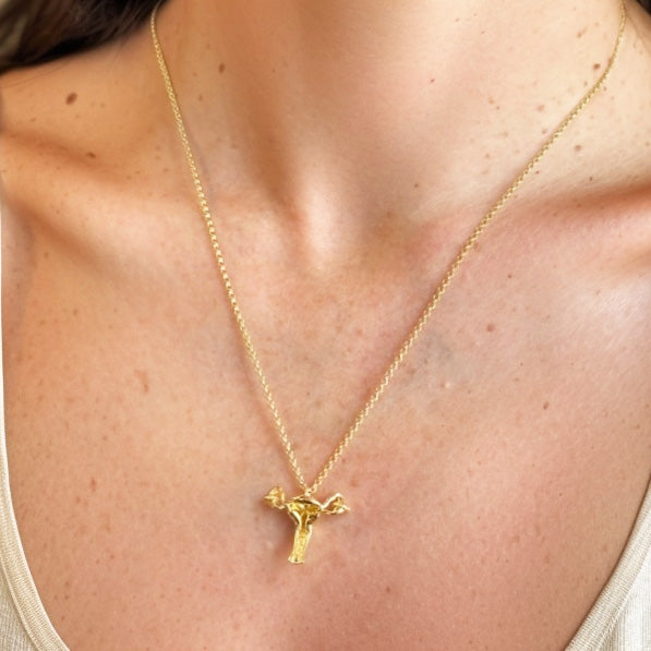 Close-up of a gold vermeil uterus necklace resting on a woman’s collarbone, highlighting its intricate anatomical details and modern design as a tribute to strength and science.