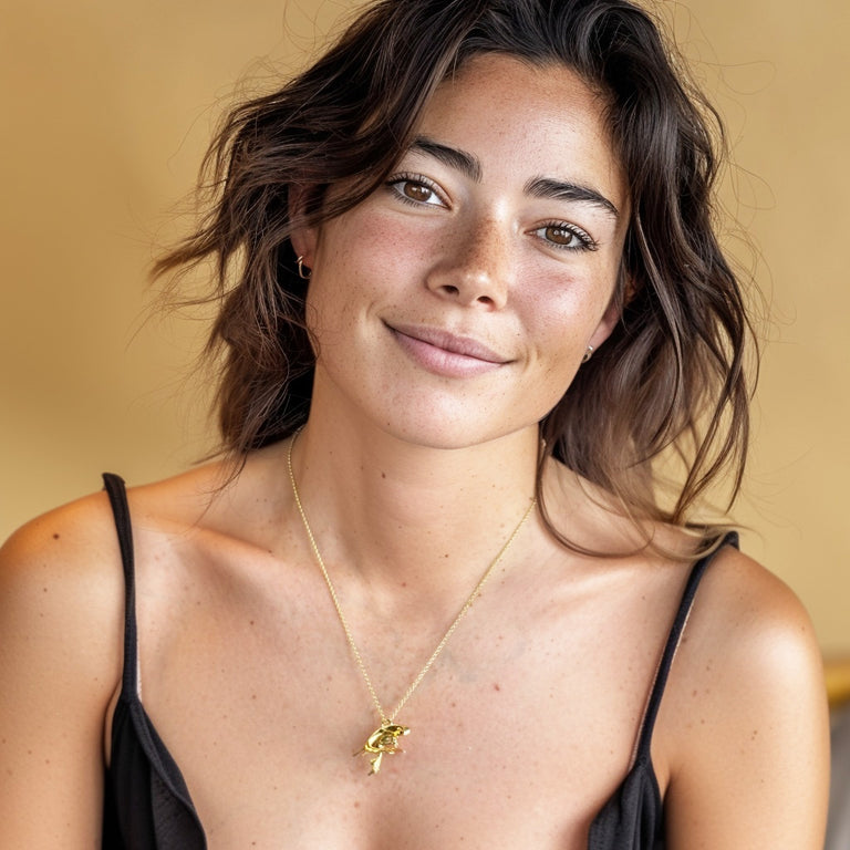 Smiling woman wearing a gold vermeil ventricular system necklace, showing how the anatomical pendant sits gracefully on the neckline.