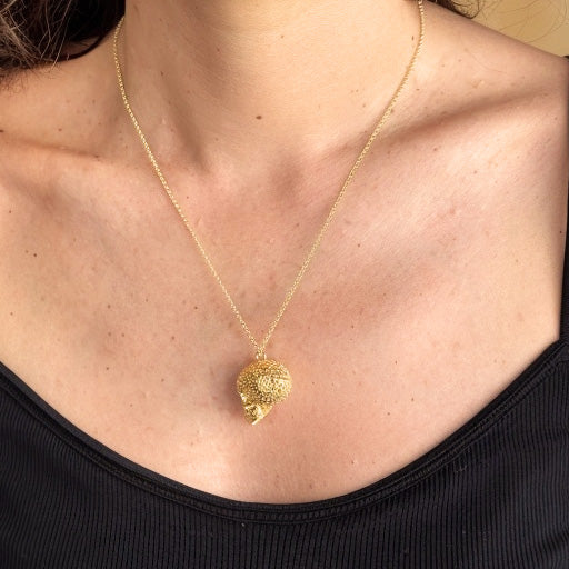 Close-up of the gold vermeil Voronoi Skull Necklace worn on a delicate chain, resting against a black tank top.