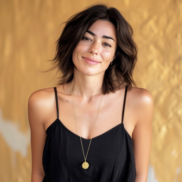 Woman wearing the West Nile Virus Necklace in gold vermeil – modern science jewelry inspired by microbiology and virology.