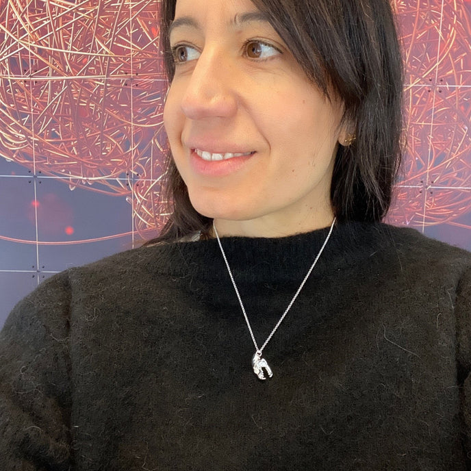 Person wearing a silver fruit bat skull necklace – unique science jewelry inspired by real fruit bat anatomy.