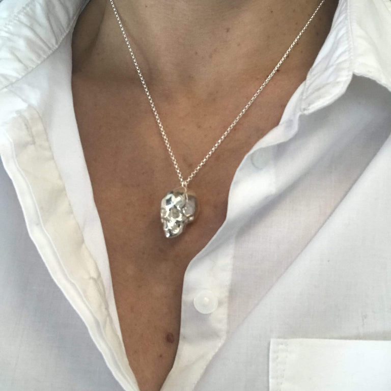 Silver skull necklace worn – edgy scientific jewelry on a white shirt.